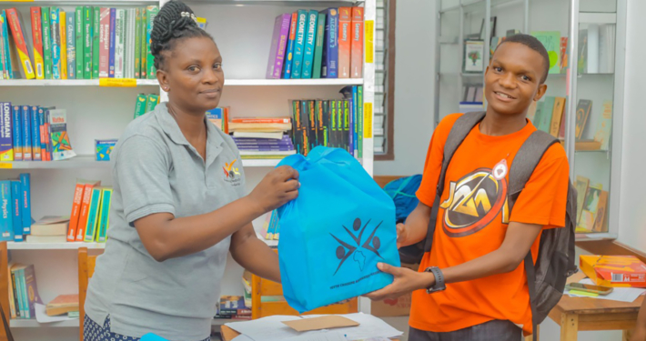 Eine Mitarbeiterin der Stiftung überreicht einem Kind ein Schulpaket
