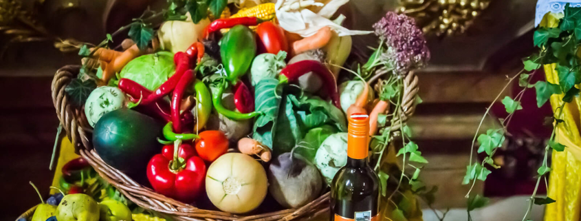 Obst und Gemüse in Körben und eine Flasche Messwein