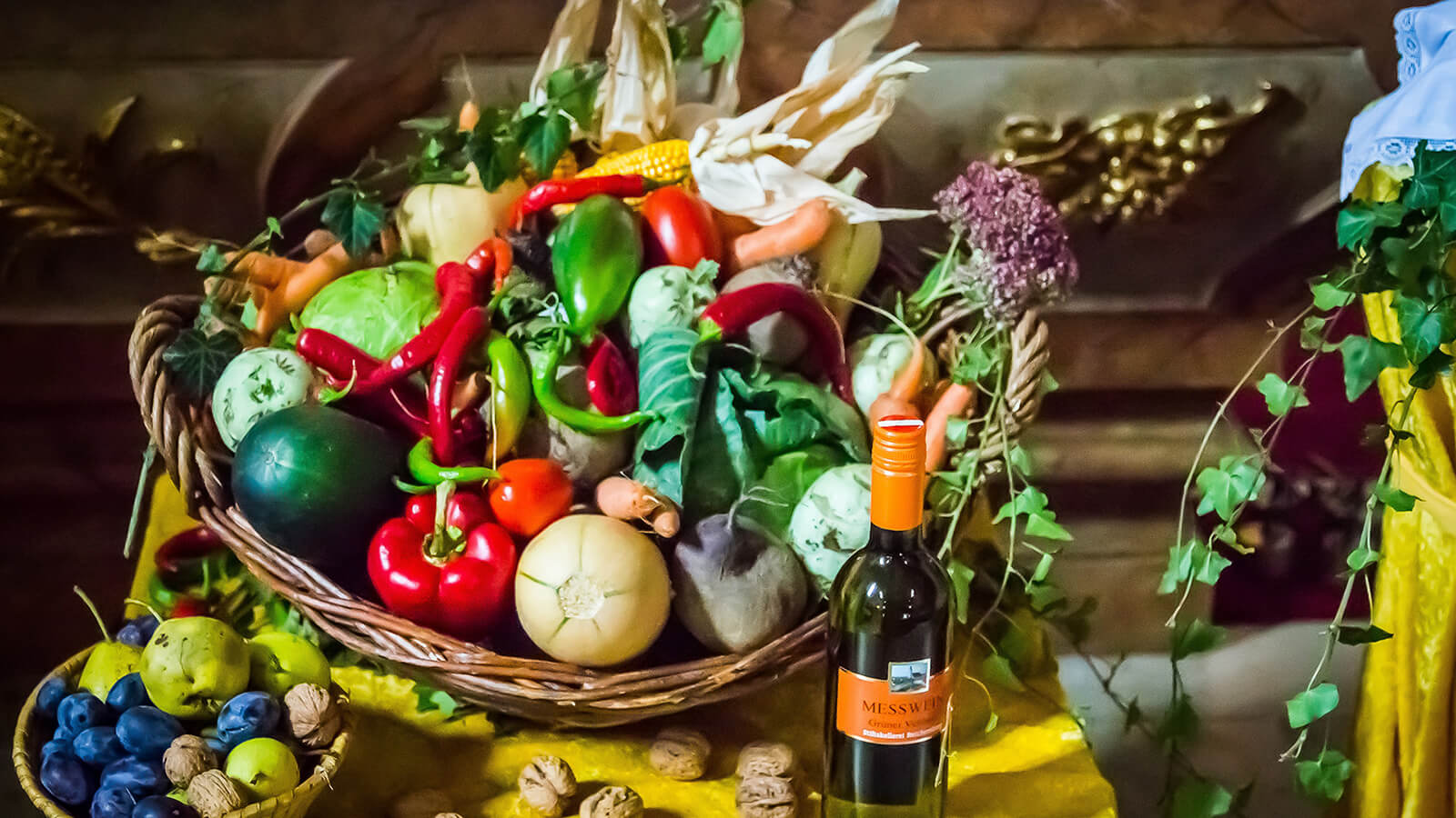 Obst und Gemüse in Körben und eine Flasche Messwein