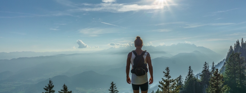 Eine Frau in Sportkleidung steht auf einem Aussichtspunkt in der Natur