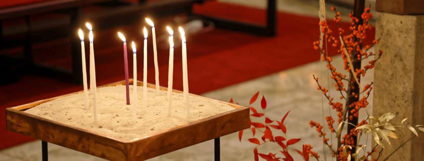 Dünne brennende Kerzen, die in der Kirche Schönbrunn-Vorpark in einem Sandbett stecken