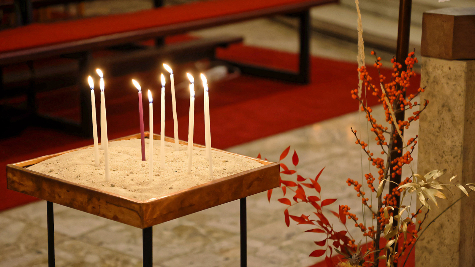 Dünne brennende Kerzen, die in der Kirche Schönbrunn-Vorpark in einem Sandbett stecken