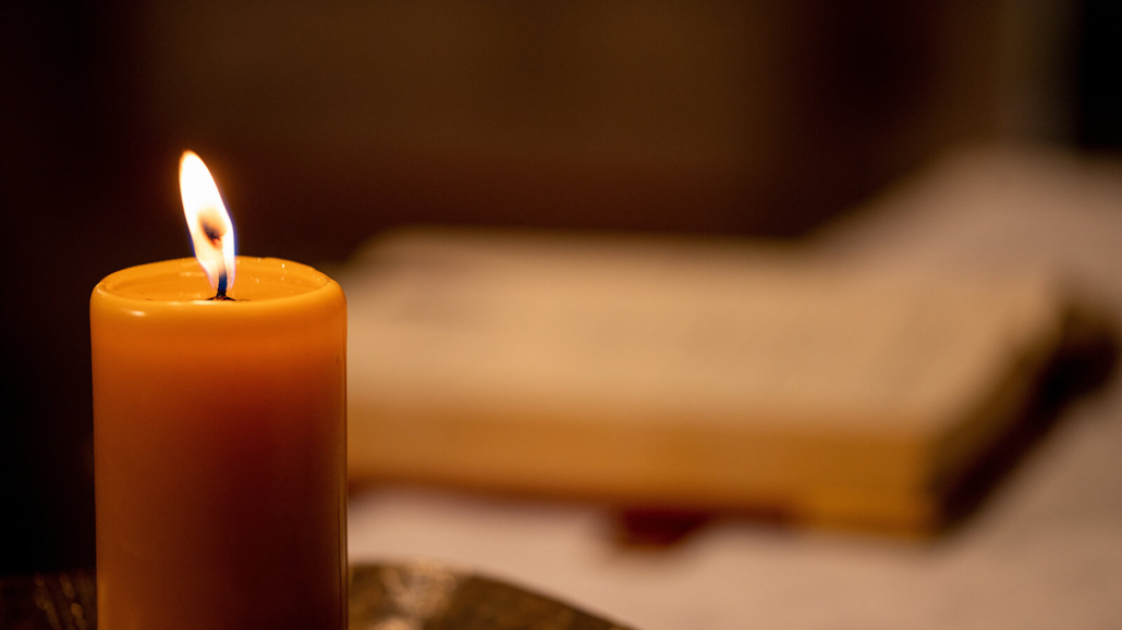 Eine brennende Kerze und ein Messbuch auf einem Altar