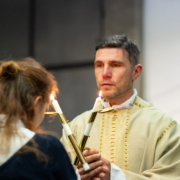 Ein Priester spendet einer jungen Frau den Blasiussegen