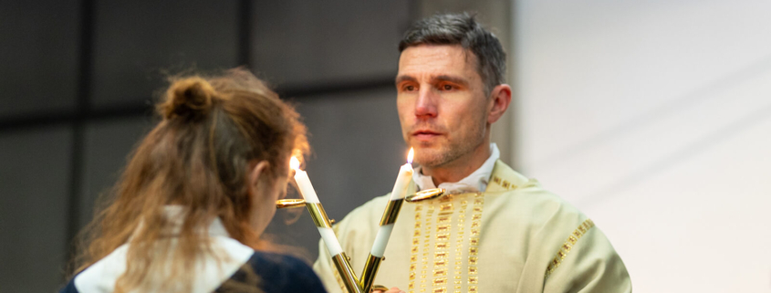 Ein Priester spendet einer jungen Frau den Blasiussegen